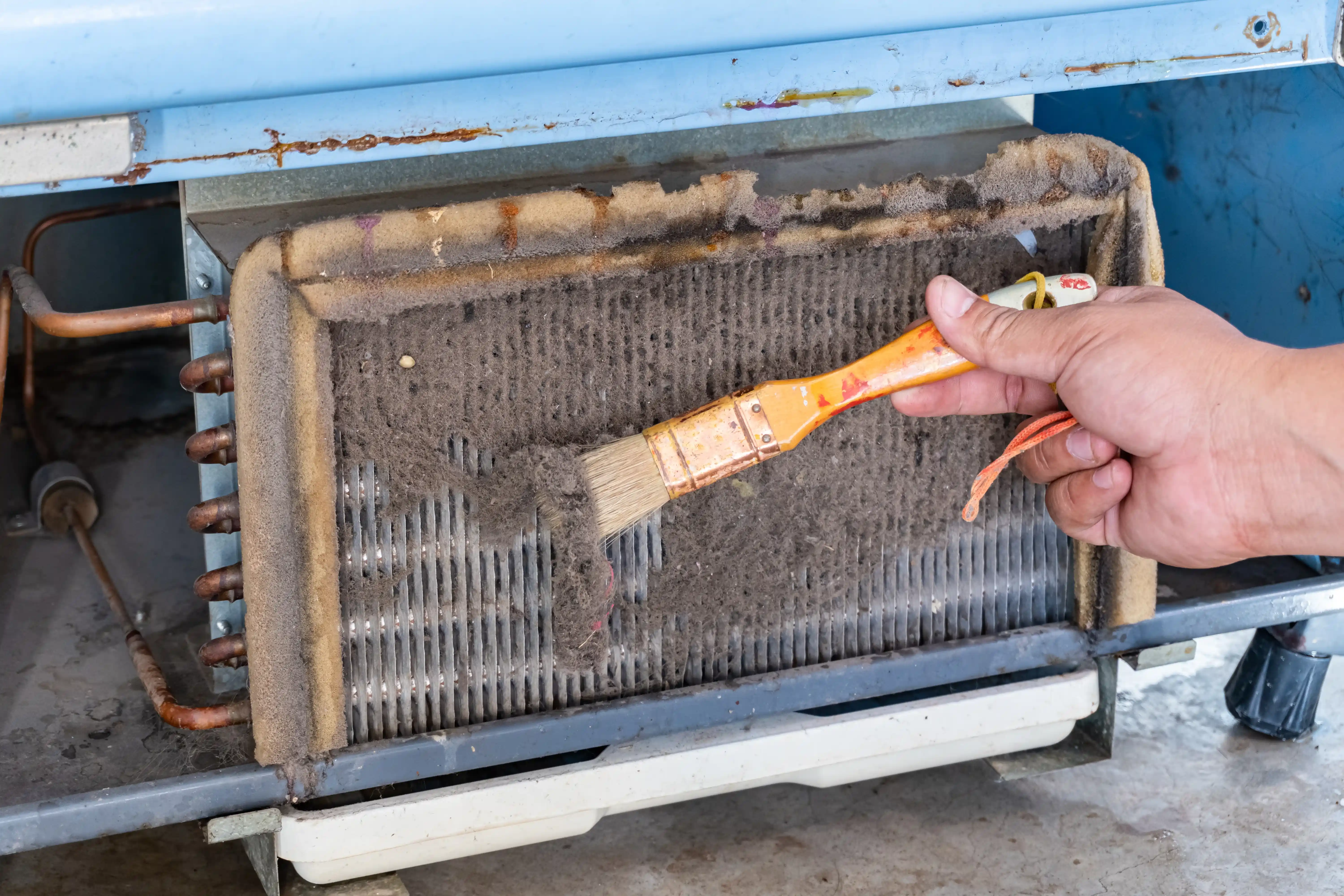 An AC TO THE MAX, INC technician cleaning a heavily clogged evaporator coil as part of an AC maintenance service in Phoenix, AZ.